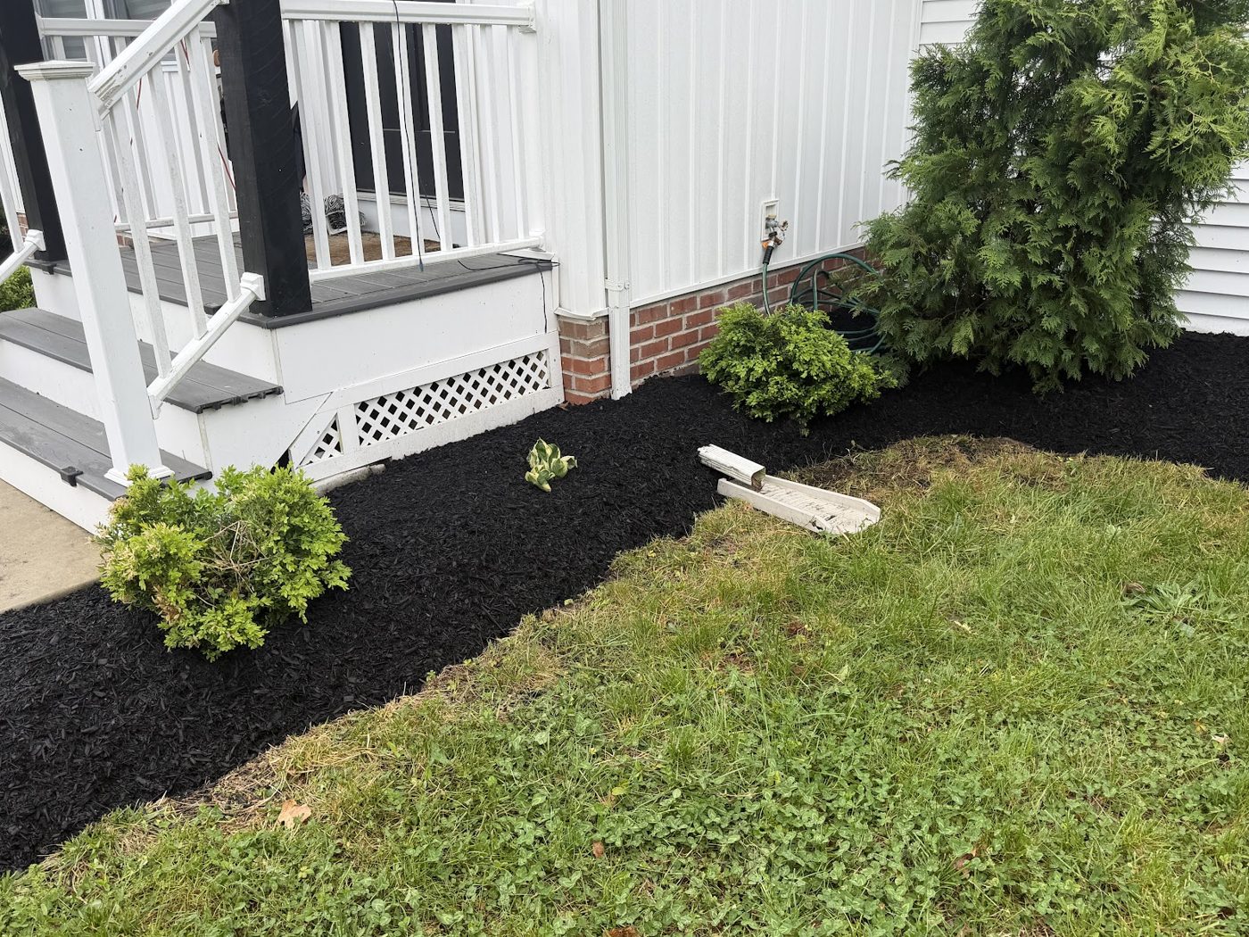 New mulch and plantings beside a white porch staircase